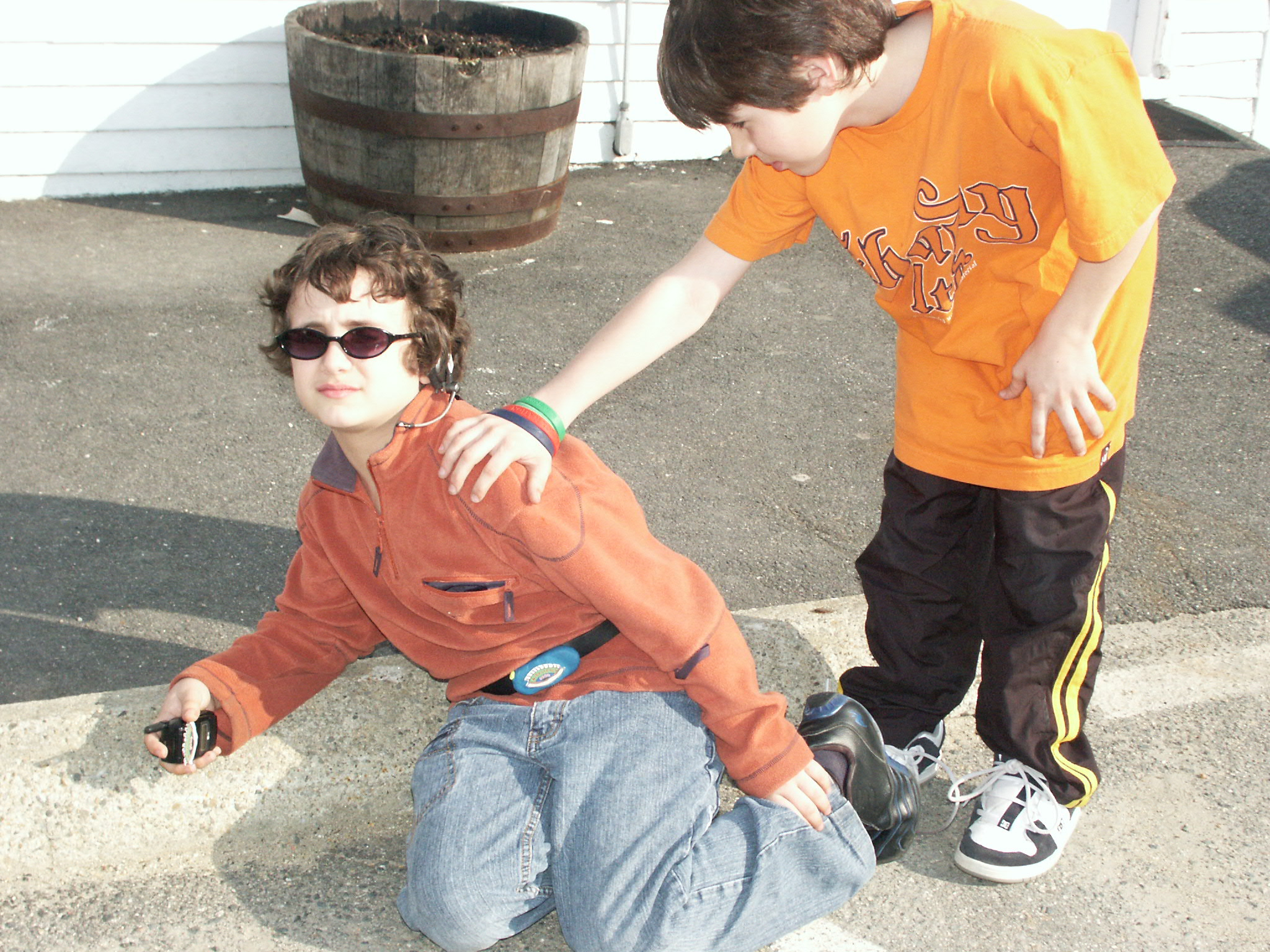 Photo of boy with hurt ankle and another boy helping him.